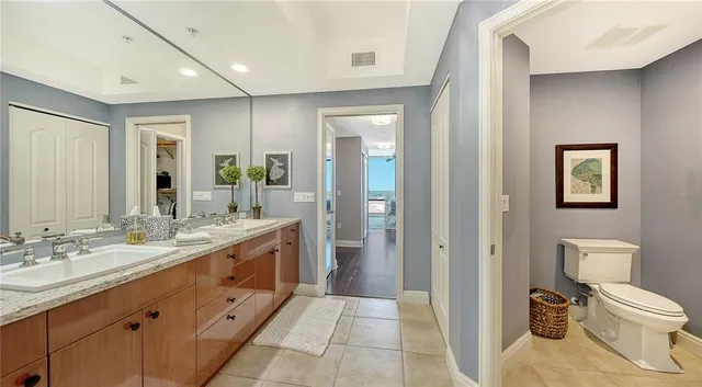 a bathroom with a granite countertop toilet sink and mirror