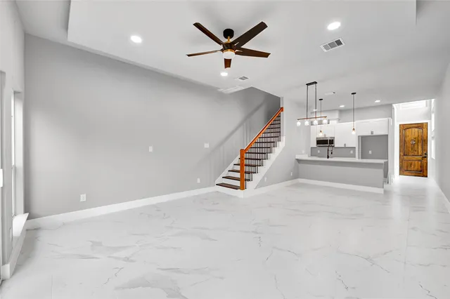 an empty room with wooden floor and a ceiling fan