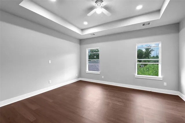 an empty room with wooden floor and windows