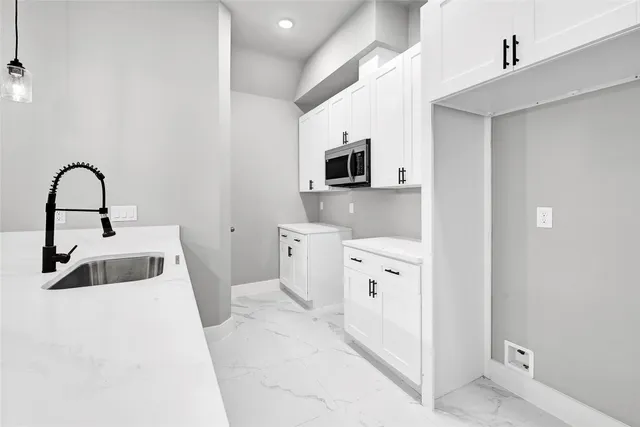 a kitchen with a sink a stove and white cabinets