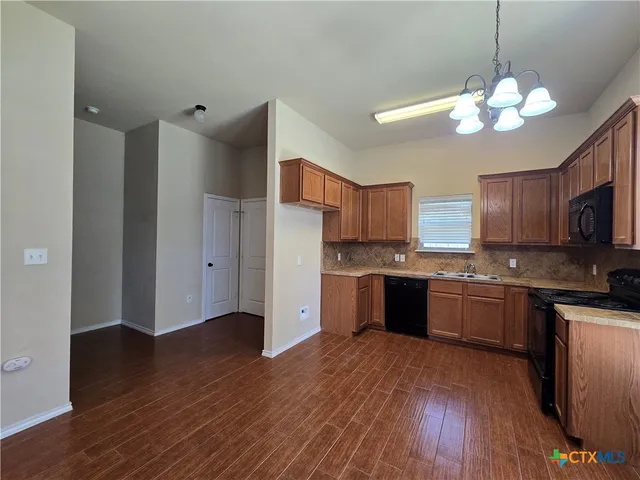 a kitchen with stainless steel appliances granite countertop a refrigerator a sink dishwasher a stove and a wooden floor