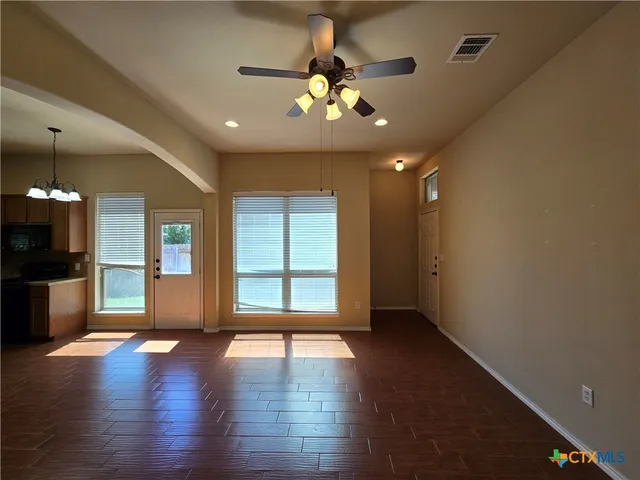 a view of an empty room with a window and wooden floor