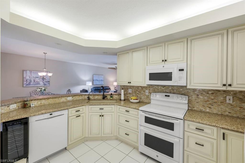 23730 Eddystone Road, Unit 5102 Bonita Springs, FL 34135 - Photo 12 of 24 a kitchen with white cabinets sink and white appliances