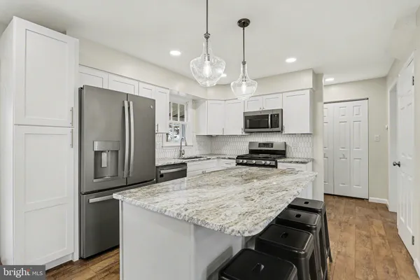 a kitchen with kitchen island granite countertop stainless steel appliances and a refrigerator