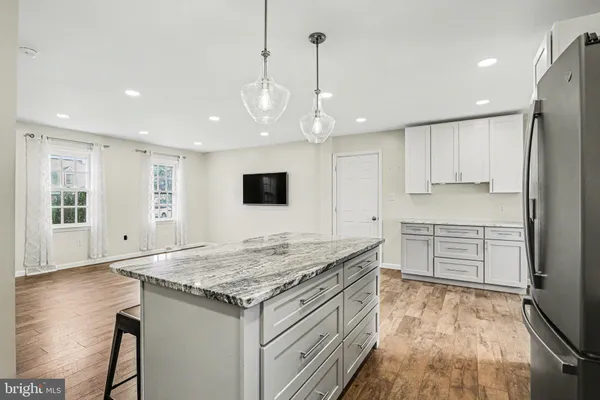 a kitchen with stainless steel appliances granite countertop a stove top oven a refrigerator a sink and chairs
