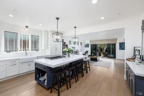a view of a kitchen with kitchen island a dining table chairs and wooden floor