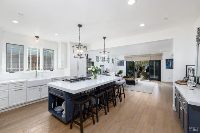 a view of a kitchen with kitchen island a dining table chairs and wooden floor