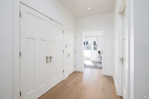 a view of a hallway with wooden floor and a bathroom