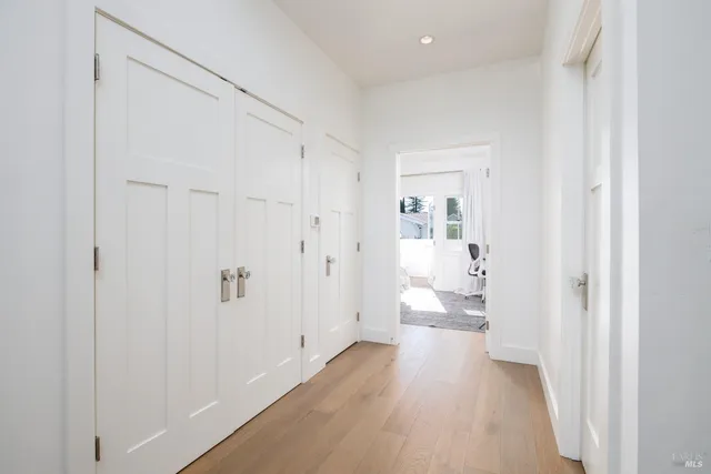 a view of a hallway with wooden floor and a bathroom