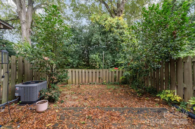 a view of a backyard with plants and trees with wooden fence