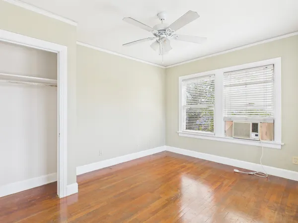 an empty room with wooden floor and windows