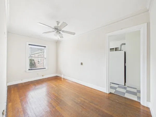 a view of an empty room with wooden floor and a ceiling fan
