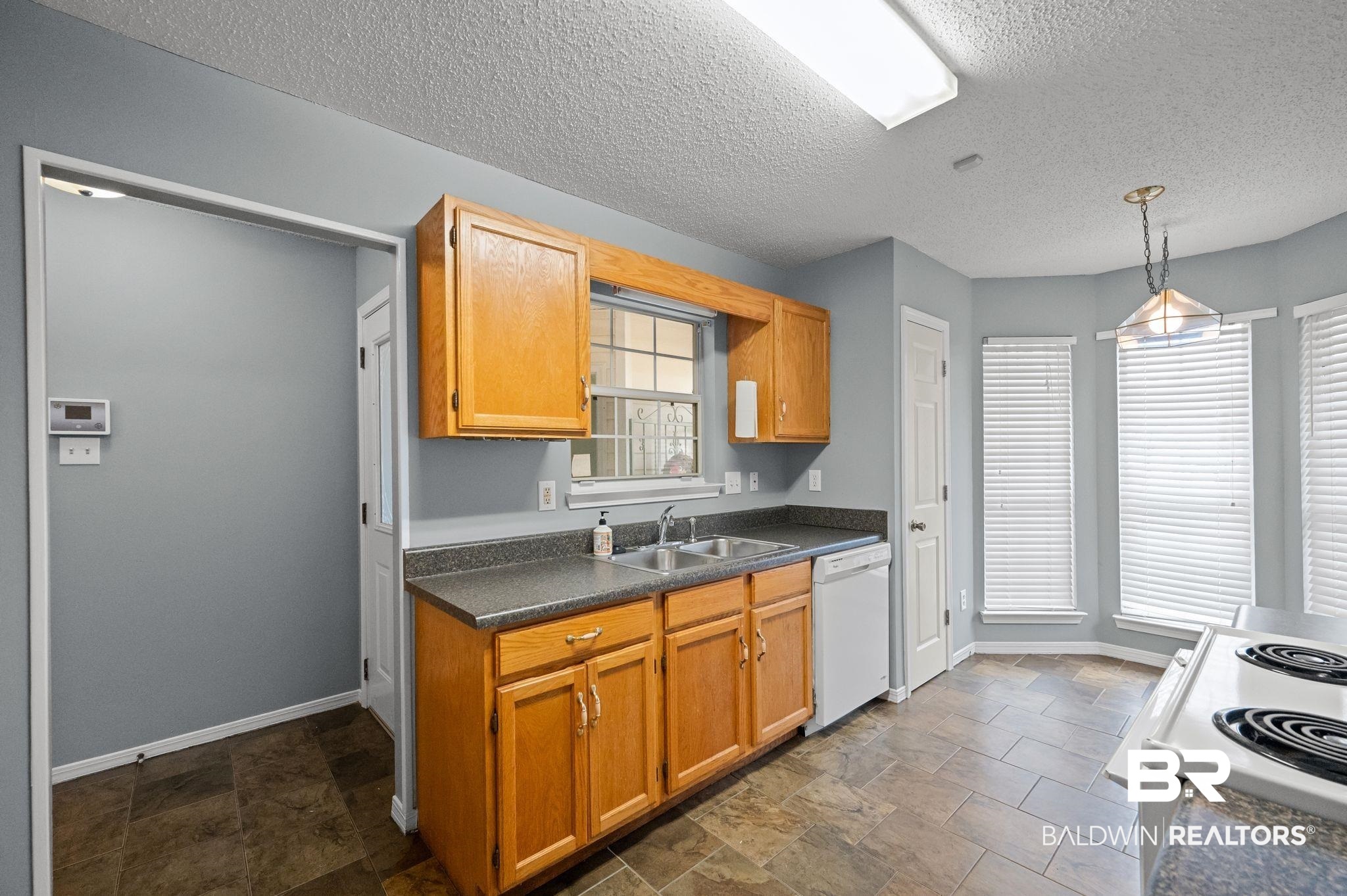 3744 Pepper Ridge Drive Mobile, AL 36693 - Photo 11 of 29 Kitchen with hanging light fixtures, stone finish flooring, white appliances, dark countertops, and a textured ceiling