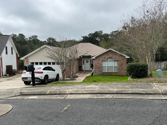 a white house with a large parking space and a car parked in front of it