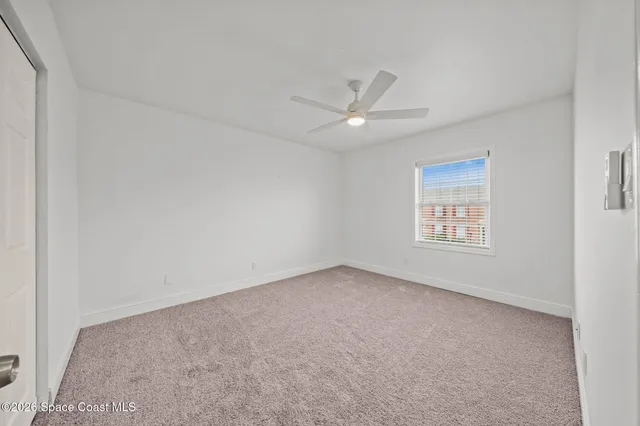 an empty room with a window and ceiling fan