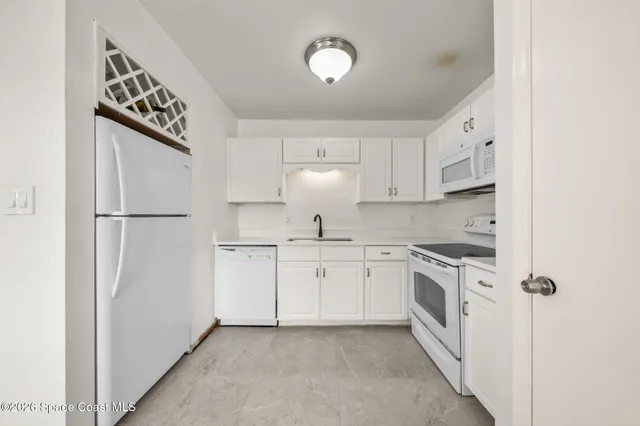 a kitchen with granite countertop white cabinets and white appliances