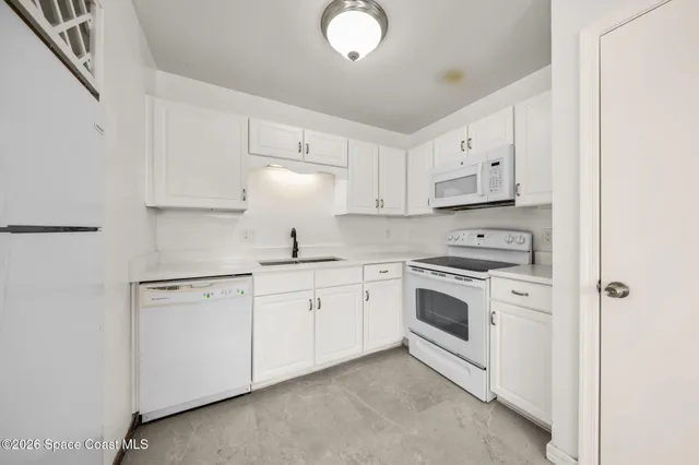 a kitchen with granite countertop white cabinets and white appliances