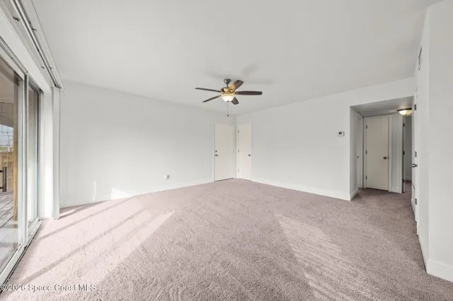 an empty room with a ceiling fan and a window