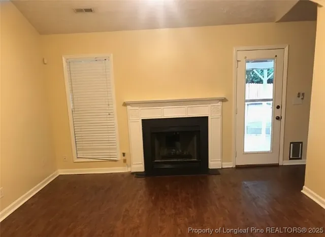a view of empty room with wooden floor and a fireplace
