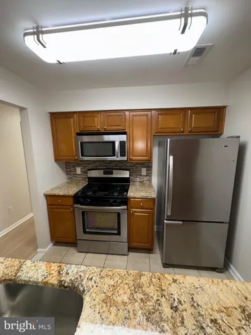 a kitchen with granite countertop a refrigerator and a stove top oven