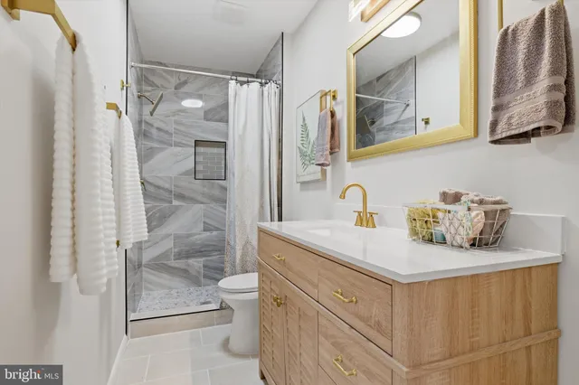 a bathroom with a granite countertop sink a toilet a mirror and shower