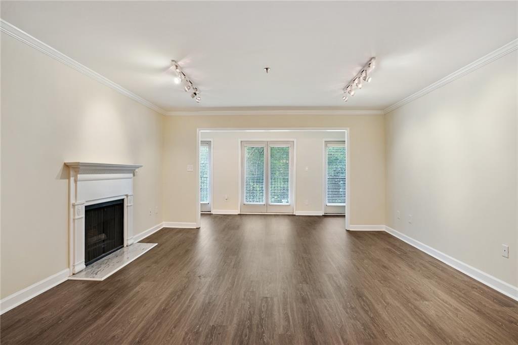 an empty room with wooden floor fireplace and windows
