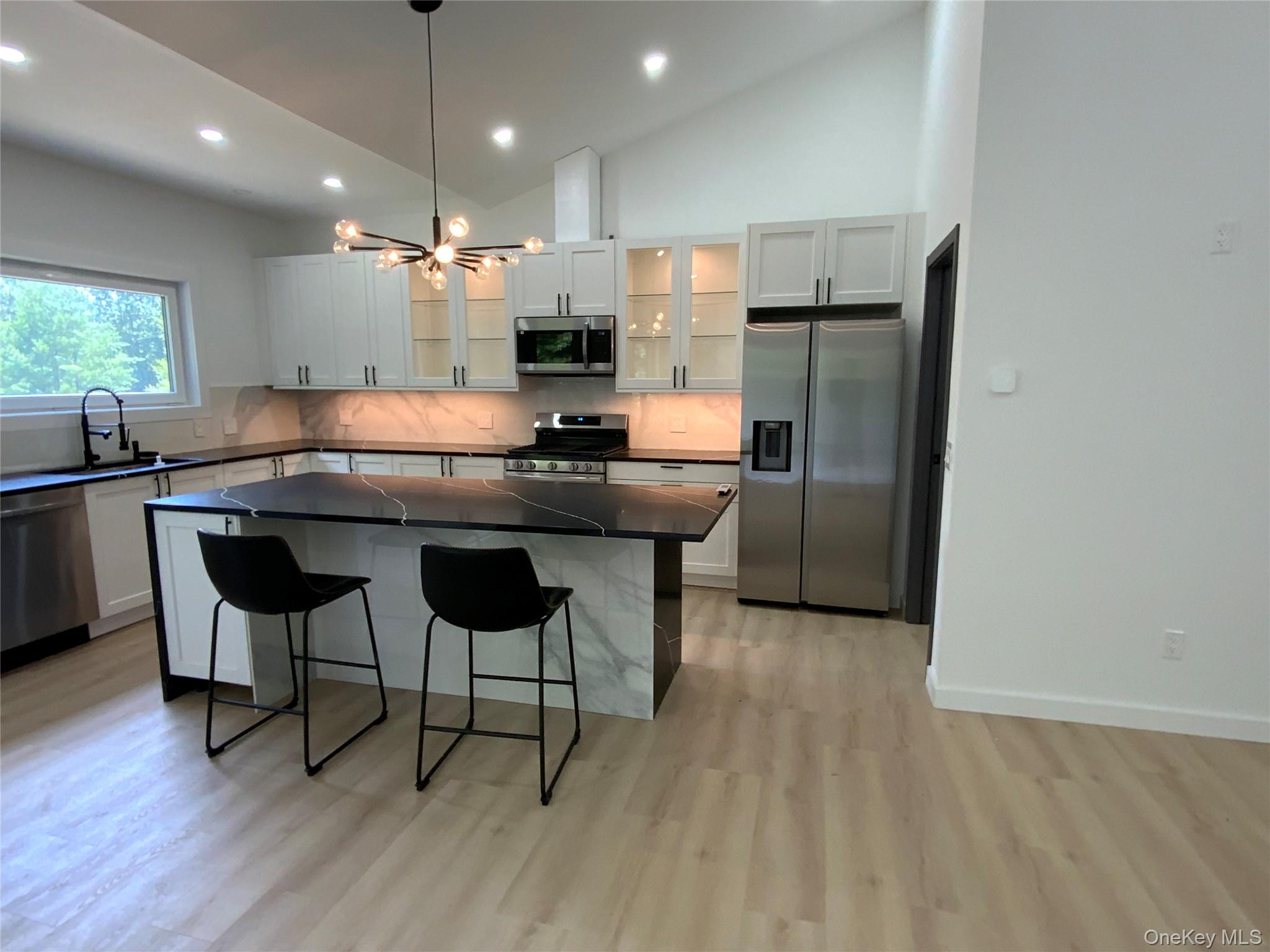 58 Dunn Town Road Wurtsboro, NY 12790 - Photo 10 of 36 a kitchen with kitchen island granite countertop a sink cabinets and wooden floor