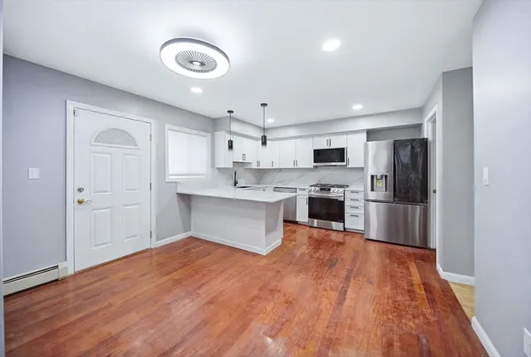 a large kitchen with a refrigerator a stove top oven a sink dishwasher and wooden floor