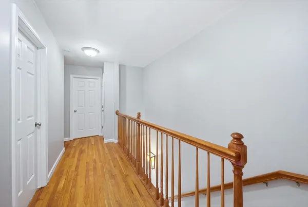 a view of a hallway with wooden floor and a bathroom