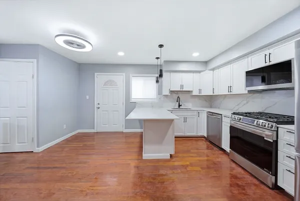 a large kitchen with cabinets a sink and stainless steel appliances