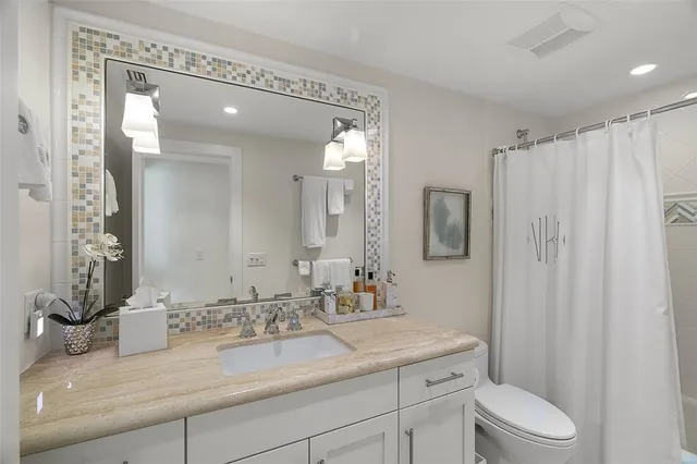 a bathroom with a granite countertop sink a toilet and a mirror
