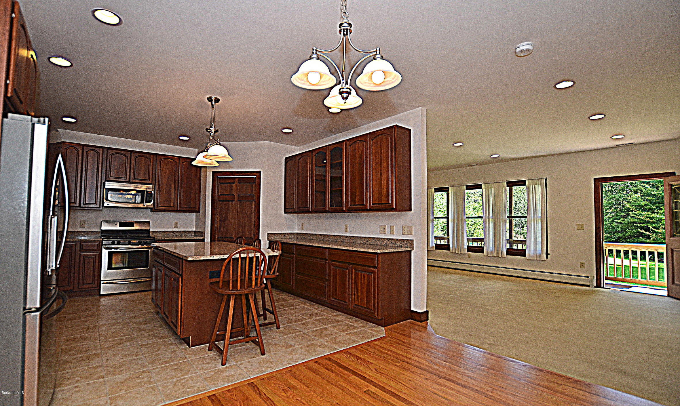 779 Stebbins Road Otis, MA 01253 - Photo 14 of 40 a kitchen with stainless steel appliances granite countertop a stove top oven a sink dishwasher a dining table and chairs with wooden floor
