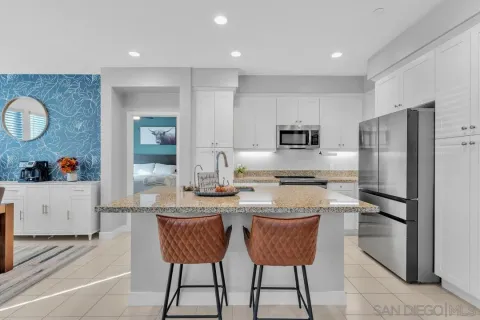 a kitchen with stainless steel appliances granite countertop a sink a stove a refrigerator cabinets and chairs