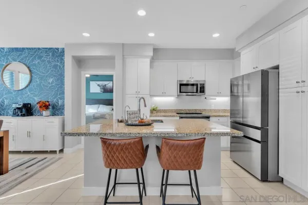 a kitchen with stainless steel appliances granite countertop a sink a stove a refrigerator cabinets and chairs