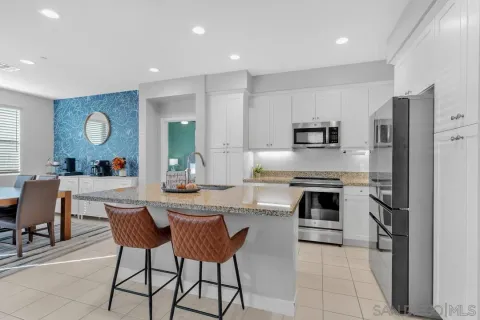 a kitchen with stainless steel appliances a stove a sink a oven a dining table and chairs