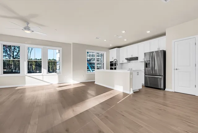 a large white kitchen with wooden floors and stainless steel appliances