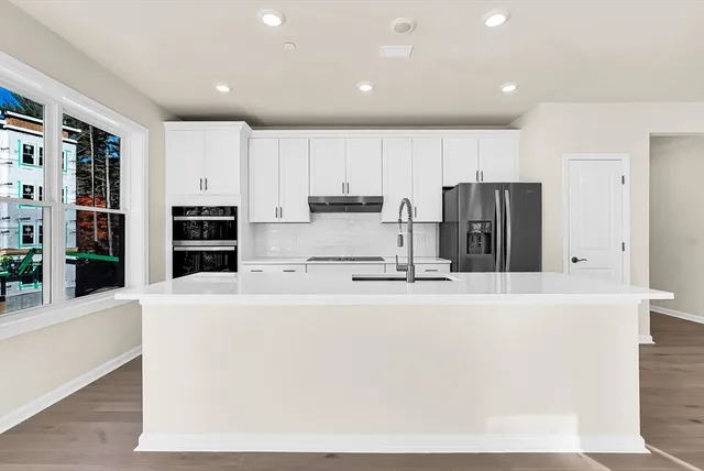 a large kitchen with stainless steel appliances a refrigerator and a stove top oven