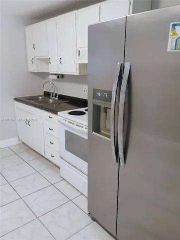 a kitchen with a refrigerator sink and cabinets