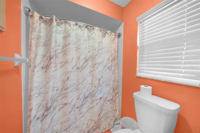 a bathroom with a toilet and a shower curtain