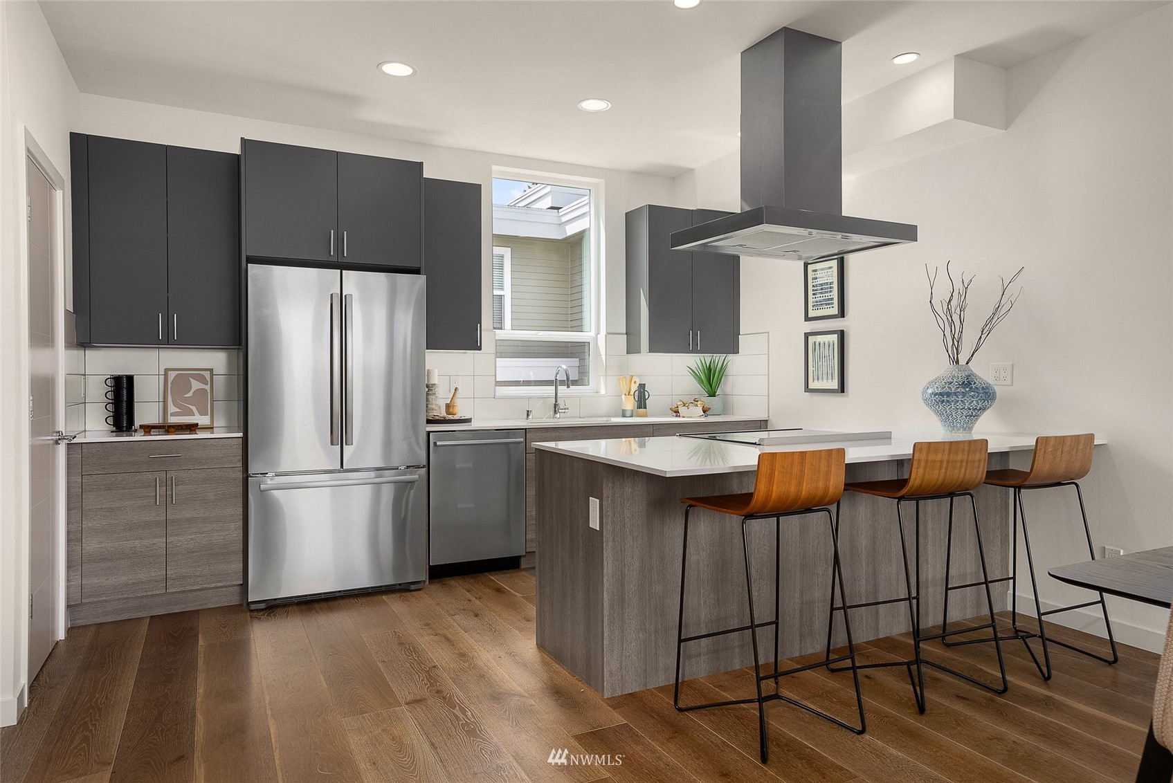4207 Southwest Frontenac Street Seattle, WA 98136 - Photo 4 of 36 a kitchen with stainless steel appliances kitchen island granite countertop a refrigerator a stove and a sink with wooden floor