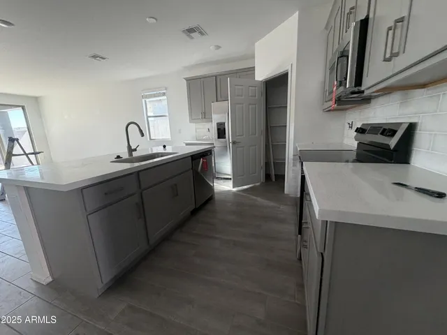 a kitchen with stainless steel appliances a sink a stove a refrigerator cabinets and a counter top space