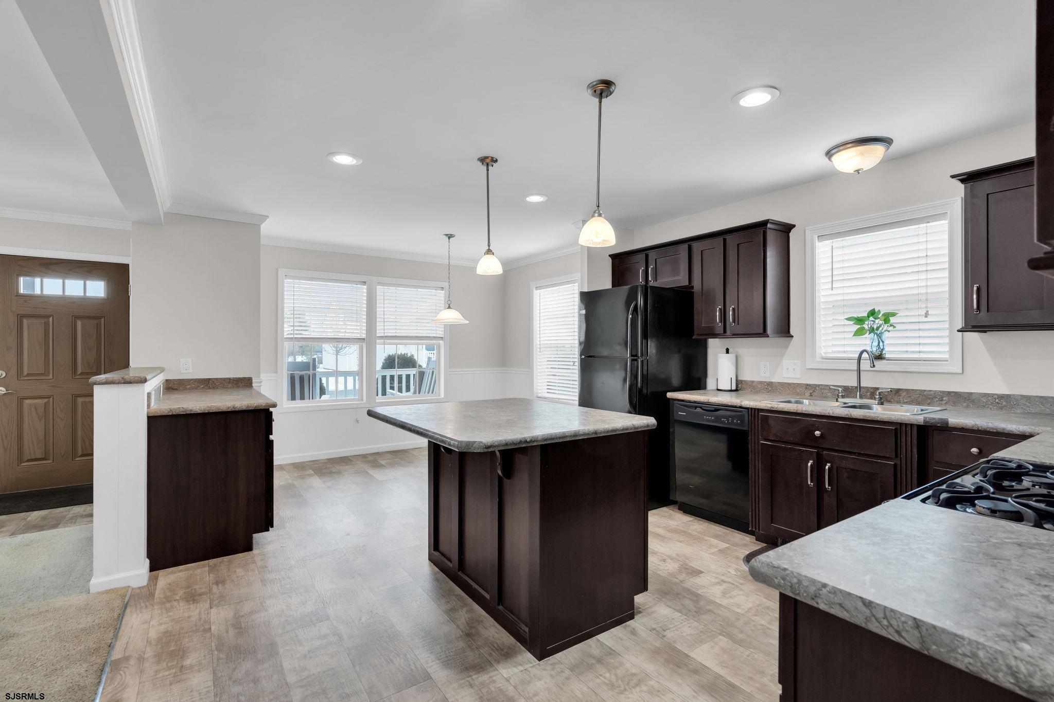 2058 South Shore Road, Unit 104 Marmora, NJ 08230 - Photo 5 of 20 a kitchen with a refrigerator a sink dishwasher with a dining table and chairs