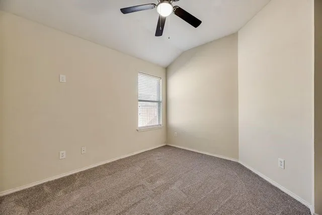 an empty room with windows and ceiling fan