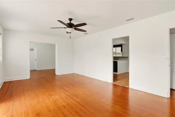 a view of empty room with wooden floor and ceiling fan