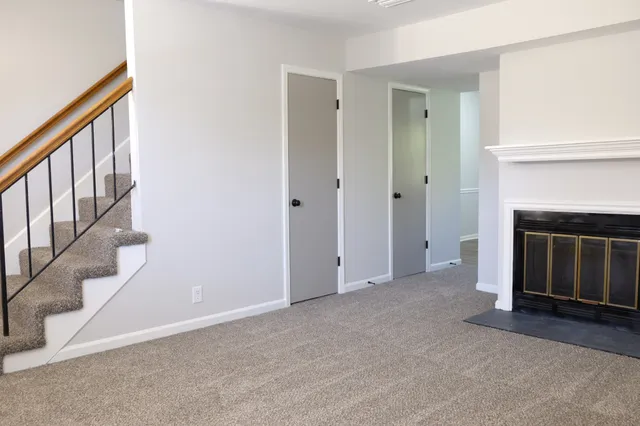 a view of an empty room with stairs and a fireplace