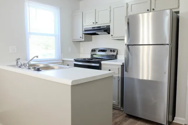 a kitchen with stainless steel appliances a refrigerator a sink and a window