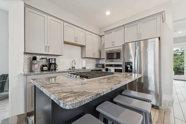 a kitchen with granite countertop a stove refrigerator and microwave
