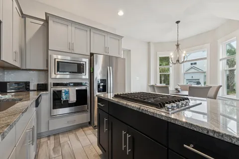 a kitchen with stainless steel appliances granite countertop a stove a sink dishwasher a refrigerator and a microwave