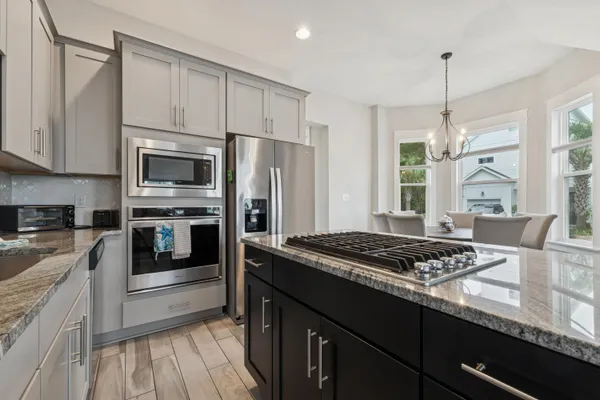 a kitchen with stainless steel appliances granite countertop a stove a sink dishwasher a refrigerator and a microwave