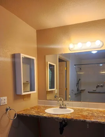 a bathroom with a granite countertop sink and a mirror
